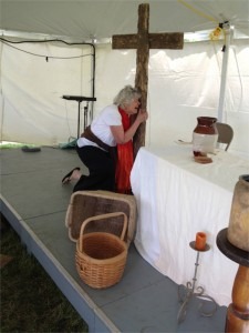 Susan kneeling at the cross during her one-woman play about Mary, mother of Jesus.